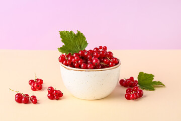 Bowl with ripe red currant and green leaves on beige background, closeup