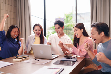 Asian adult professionals celebrating project success reviewing data team meeting modern office