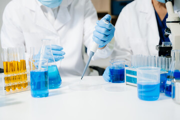 scientists in lab coats conducting research, handling glassware, and working with chemicals in a...