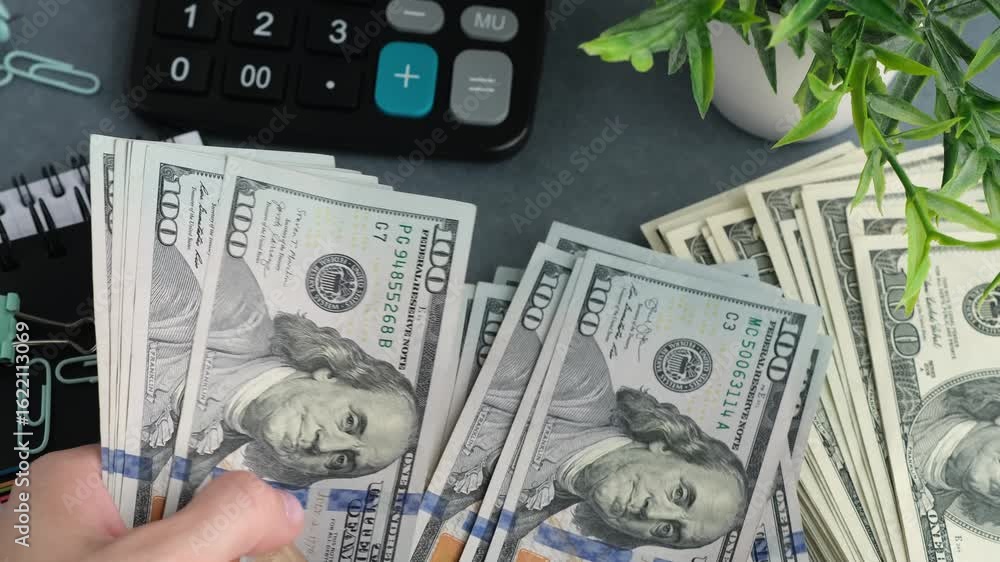 Poster a person is holding a stack of us dollars. the stack contains a total of 100. the person is standing