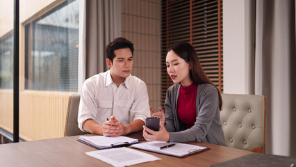 Asian business professionals collaborate discuss project details sharing information on smartphone during office meeting corporate environment