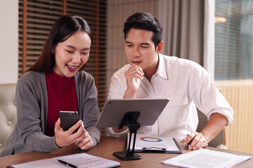 Asian adult business professionals collaboratively analyze data discuss innovative strategies utilizing tablet smartphone technology for corporate growth in modern office settings