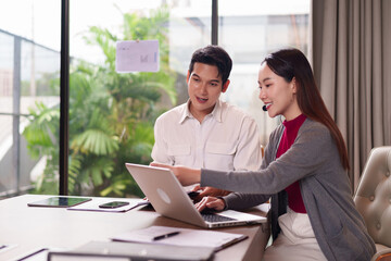 Asian business professionals collaborate project using laptop computer headset discussing sales strategy modern bright office meeting room green environment
