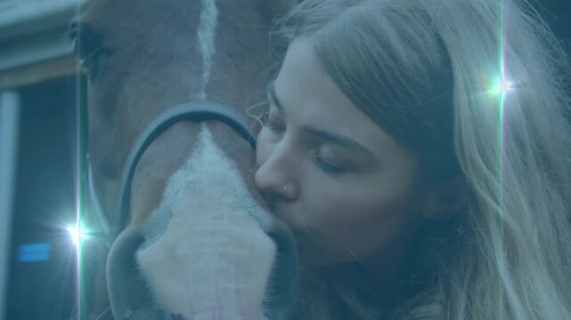 Equine therapist pressing cheek against horse muzzle and creating lens flare by barn wall
