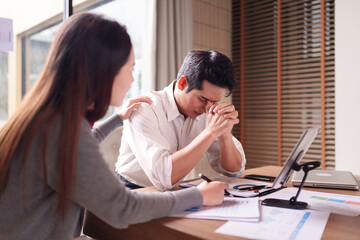 Asian business professional woman comforts male colleague facing work stress or personal challenge...