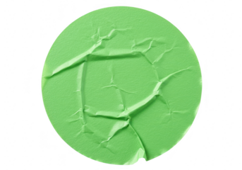 A crumpled green circular sticker with visible creases and folds isolated against a stark transparent background