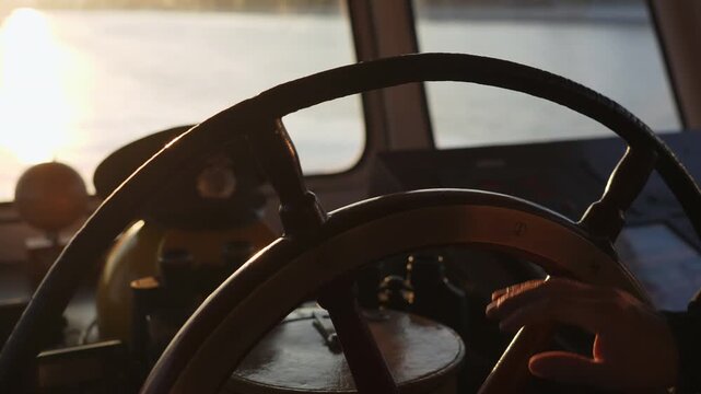 Captain steering ship wheel on bridge during golden hour. Clip