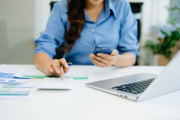Women counting coins on calculator taking from the piggy bank. hand holding pen working on calculator to calculate on desk about cost