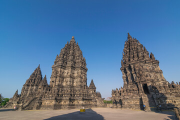 View of Prambanan temple, a UNESCO World Heritage site. Under a brilliant clear blue sky, the massive, intricately carved stone structures rise majestically, located on Klaten, Indonesia.