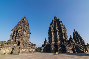 View of Prambanan temple, a UNESCO World Heritage site. Under a brilliant clear blue sky, the massive, intricately carved stone structures rise majestically, located on Klaten, Indonesia.