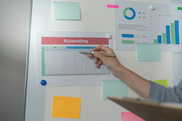 Accounting Overview. Hand pointing at financial data on a presentation board.
