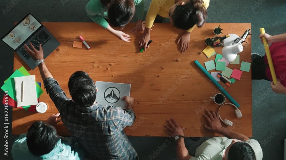 Poster top view of business team put graphic logo on meeting table with laptop and paper and start to desig