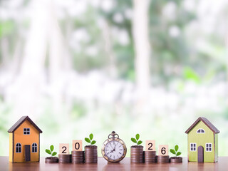 Miniature house, Vintage watch and plants growing up on stack of coins. The concept of saving money...
