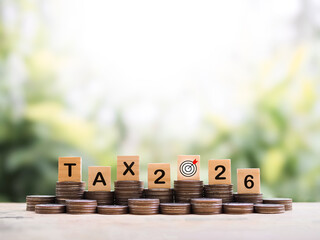 Wooden blocks with the word TAX and Number 2026 on stack of coins. The concept about saving money...