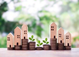 Miniature house and plants growing up on stack of coins. The concept of saving money for house,...