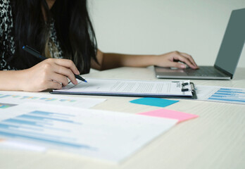 Young Asian business woman sitting at the table holding a pen, r