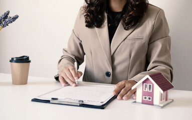 Beautiful real estate agent signs documents and gives home insurance advice Create a home purchase...