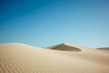 Clean, minimalistic shot of smooth sand dunes under a clear blue sky