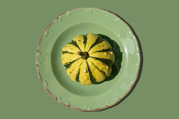 Colorfull yellow small pumpkin in green plate