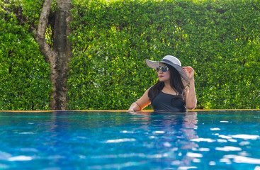 Summer day lifestyle woman relax and chill near luxury swimming pool sunbath at the beach resort outdoors the hotel. Summer Concept