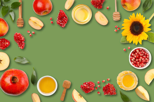 Fresh apples pomegranates and honey displayed creatively on green