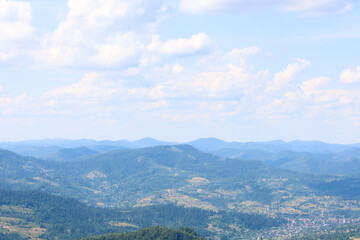 A massive mountain range, covered with dense forests, stretches to the horizon, where it dissipates into a light haze. The image illustrates the majesty, tranquility, and natural beauty of the mountai