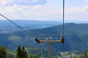 A chairlift on a mountain slope covered with a dense forest creates a feeling of travel and unity with nature. The image perfectly conveys the atmosphere of relaxation, adventure, and freedom, making 