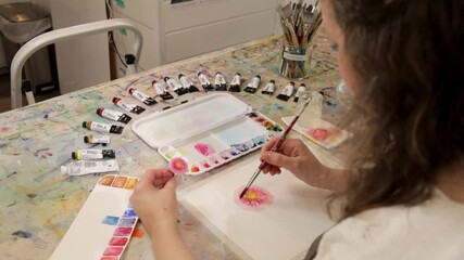 Watercolor painter paints pink flower, seen from above - Powered by Adobe