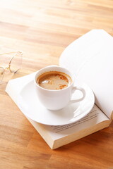ページを開いたペーパーバック（洋書）とコーヒーの入ったコーヒーカップで、コーヒーを飲みながら読書を楽しんでいるイメージ
