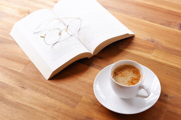 ページを開いたペーパーバック（洋書）とコーヒーの入ったコーヒーカップで、コーヒーを飲みながら読書を楽しんでいるイメージ
