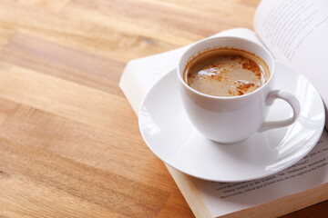 ページを開いたペーパーバック（洋書）とコーヒーの入ったコーヒーカップで、コーヒーを飲みながら読書を楽しんでいるイメージ
