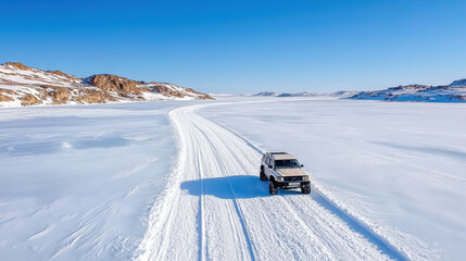 Aerial view of vehicle driving frozen landscape, showcasing vast snow covered terrain and clear