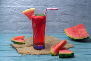 Refreshing summer drink with watermelon and ice in a glass, decorated with fruit slices, mint, and...
