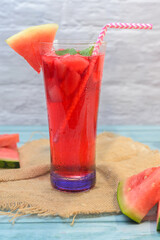 Refreshing summer drink with watermelon and ice in a glass, decorated with fruit slices, mint, and...