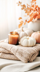 Cozy autumn scene featuring decorative pumpkins, a warm candle, and soft knitted blankets, creating a welcoming atmosphere for seasonal decor
