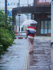 雨の日に高山駅前の街で歩く一人の中年男性の姿