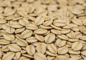 Macro shot of light brown rolled oats, revealing their distinct flattened shape and natural patterns.

