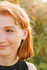 Red-haired woman smiling with long earrings in sunflower field
