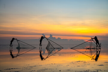 Fishermen at Quang Lang beach, Thai Binh, casting nets at sunrise. A glimpse into coastal life and...
