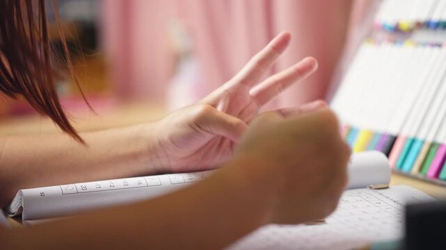 Two elementary school girls are studying at their desks at home. Two cute schoolgirls are diligently doing their homework.