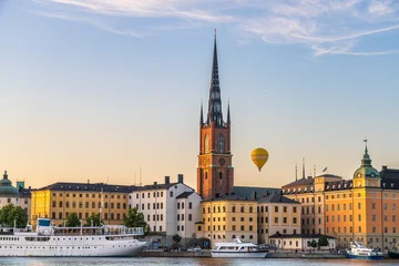 Canvas schilderij Stockholm View of the Riddarholmen Church's spire piercing the skyline amidst historical buildings and a floating hot air balloon, Stockholm, Sweden.  © John N
