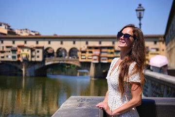 Woman in white dress standing on bridge over Arno river in Florence Italy