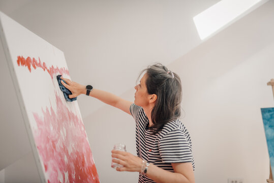 Female artist cleaning painting in art studio with cloth