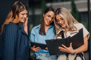 Businesswomen reading documents and using tablet outdoors