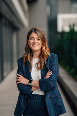Smiling businesswoman posing with folded arms in urban setting