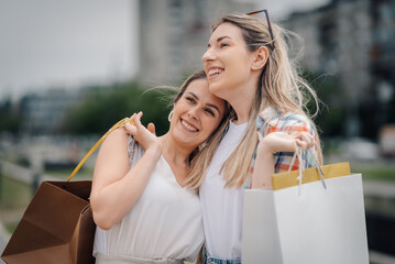 Two happy women carrying shopping bags, enjoying a day of shopping