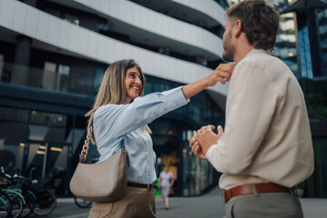 Businesswoman adjusting businessman's collar in front of modern building