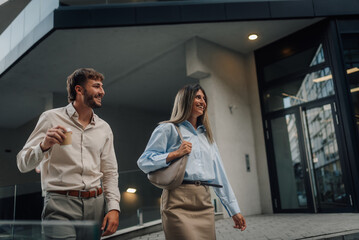 Business partners leaving the office building, walking and talking during coffee break