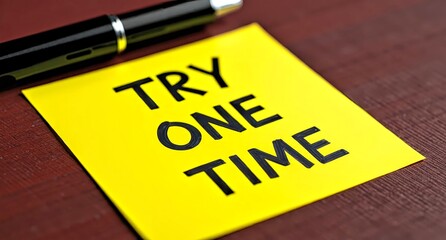 Yellow Sticky Note with 'Try One Time' Message and Pen on Table
