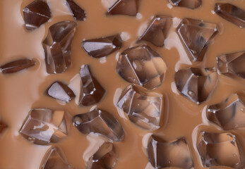 Cold iced coffee texture close up detail with ice cubes, summer holiday drink background.